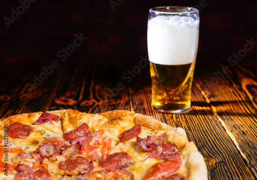 Obraz na płótnie Tasty pepperoni pizza on wooden table near a glass of beer w salonie