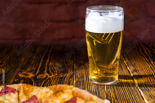 Tasty pizza on wooden table near a glass of beer