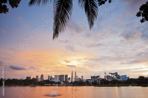 Beautiful sunset in Kuala Lumpur with palm leaves in the foreground  © pop_gino