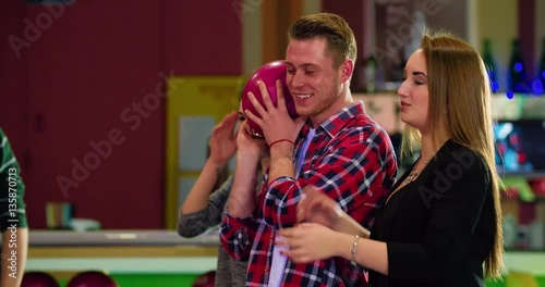 Friends playing and having fun at bowling 4k leisure video. Young man holds the ball, prepares for rolling. Game players talking and laughing
