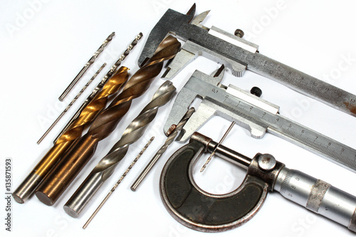Drill bits and micrometer screw caliper on white background