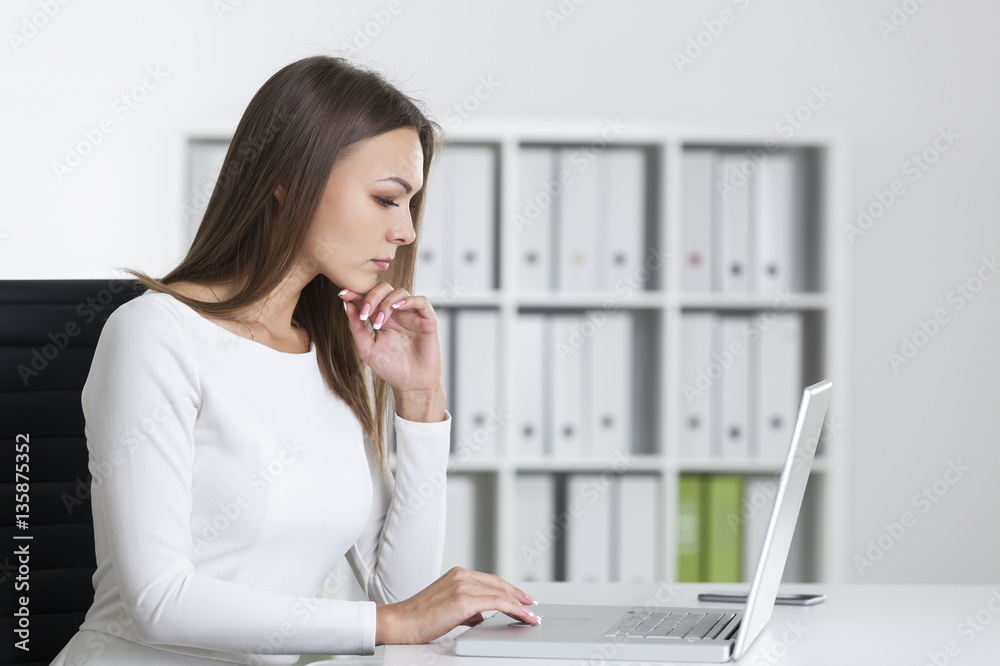 Side view of a serious woman at laptop Side view of a serious woman at laptop