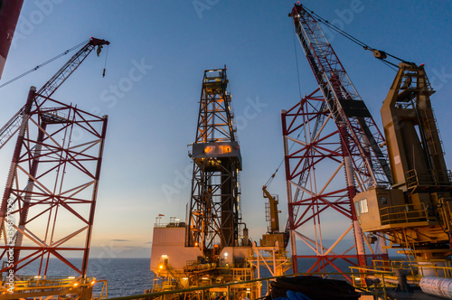 Offshore jackup drilling rig's legs with view of derrick and crane in background.