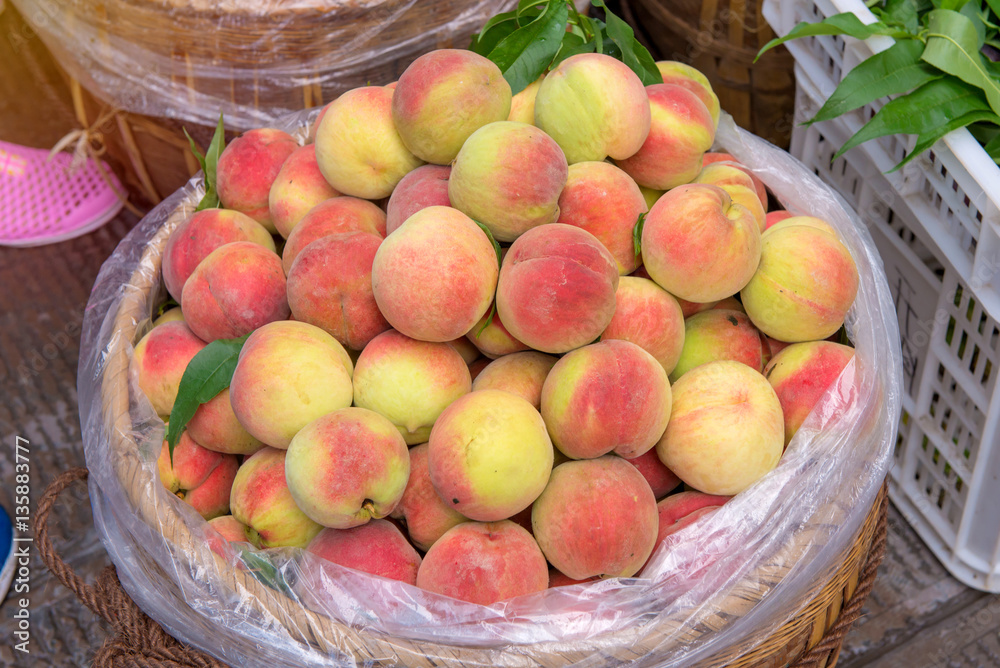 Fresh peaches in a wooden basket at the fruit market