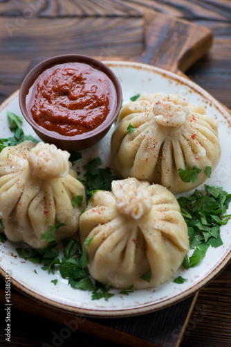 Closeup of khinkali dumplings with satsebeli sauce and coriander