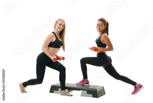 Fototapeta Naklejka Na Ścianę i Meble -  Two fit women exercising at step-aerobics class