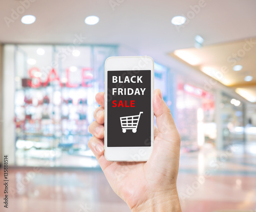 Hands holding mobile phone with Black Friday sale on screen on b