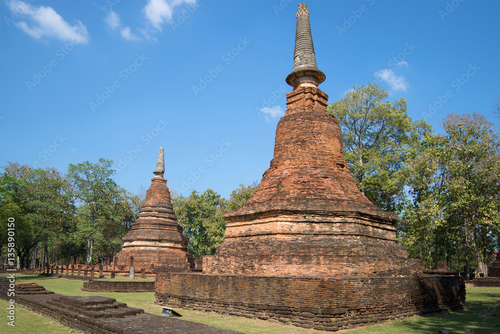 Fototapeta premium Two chedi on the ruins of ancient Buddhist temple Wat Phra That. Kamphaeng Phet, Thailand