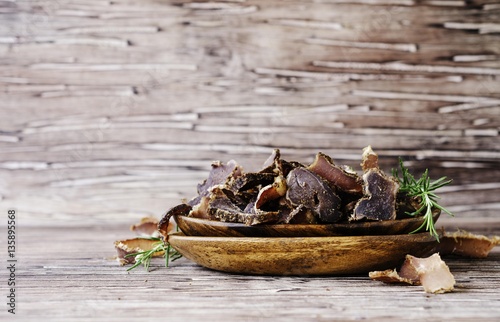 jerked meat, cow, deer, wild beast or biltong in wooden bowls on a rustic table