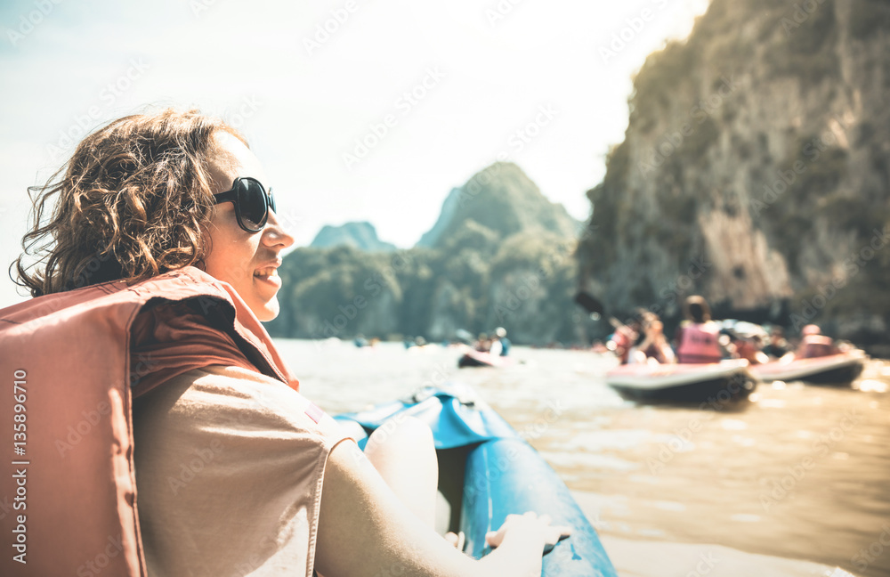 Naklejka premium Young woman traveler with life jacket enjoying sunset ride on kayak island hopping - Wanderlust and travel concept with adventure girl tourist traveler on excursion in Thailand - Retro sunshine filter
