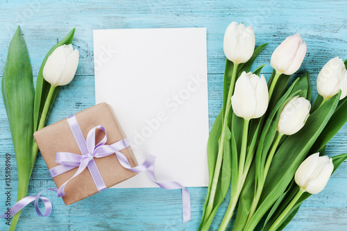 Fototapeta Naklejka Na Ścianę i Meble -  Spring tulip flowers, gift box and paper card on turquoise vintage table from above in flat lay style. Greeting for Womens or Mothers Day.