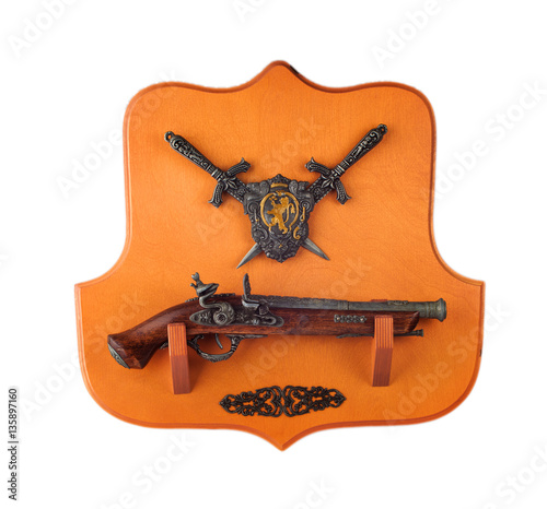 miniature pistol, daggers and coat of arms on the wooden  backgr photo