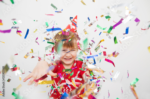 Little boy having fun celebrating birthday. Portrait of a child throws up multi-colored tinsel and confetti. Positive emotions.