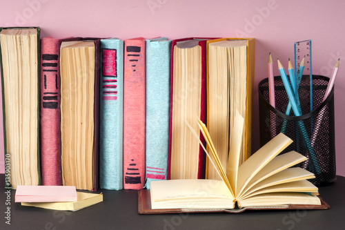 Open book, stack of colorful hardback books on light table. Back to school. Copy space for text