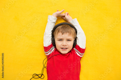 little boy with headphones on yellow background
