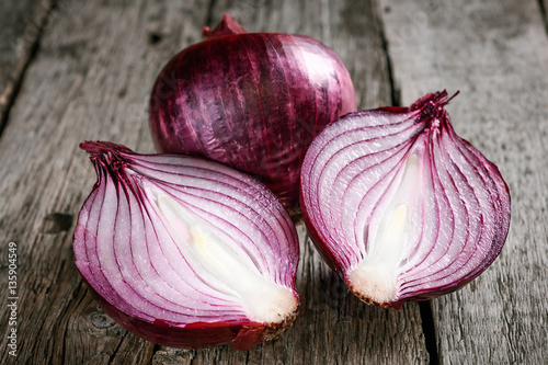 close up of sliced red onion and whole red onion on a wooden tab