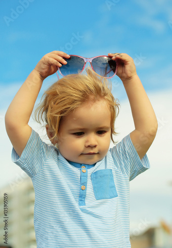 Cute baby boy puts fashionable sunglasses on head