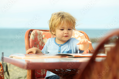 Cute baby boy reads menu card