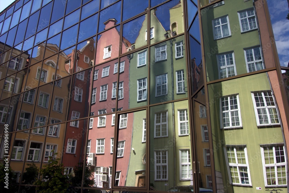 Colorful tenement houses reflected in windows of modern building