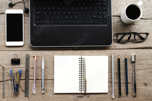 Top view of office desk  Laptop  Phone  Notebook  Pen  Glasses  Coffee on wooden desk