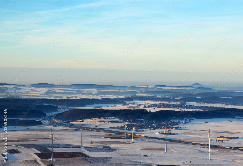 Aerial view  of wind turbines and german highway  in snowy southern germany on a sunny winter day (south of the swabian alps)