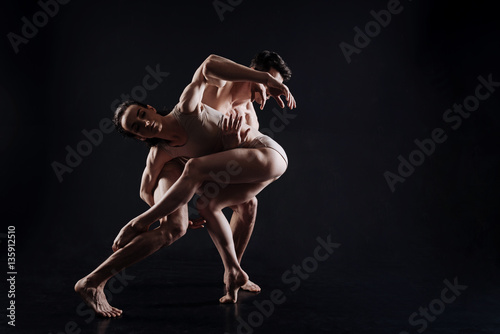 Flexible gymnasts performing in the black colored studio