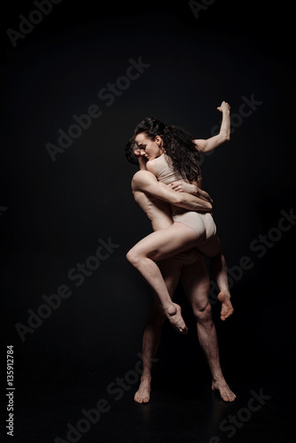 Expressive young performers dancing against black background