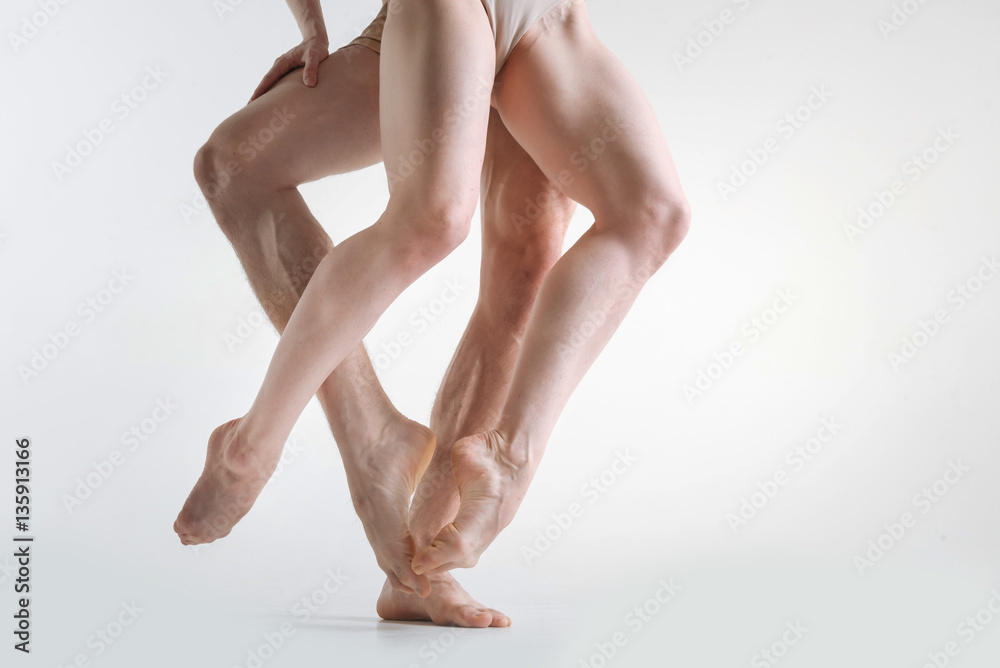 Muscular athletes legs dancing in the white colored studio Muscular athletes legs dancing in the white colored studio