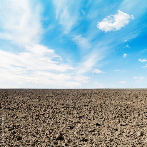 arable field and white clouds in blue sky