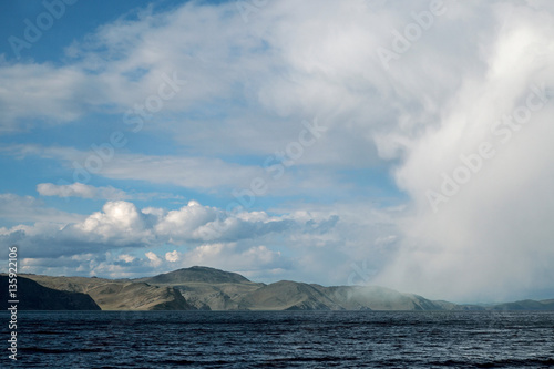 Big cloud in the form of man   s face hangs down just over water and mountains