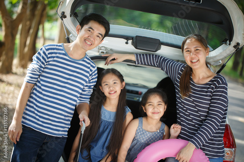 Happy Asian family with mini van are smiling and preparing for travel on summer holiday