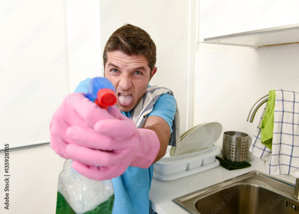 young lazy house cleaner man washing and cleaning the kitchen with detergent spray bottle young lazy house cleaner man washing and cleaning the kitchen with detergent spray bottle