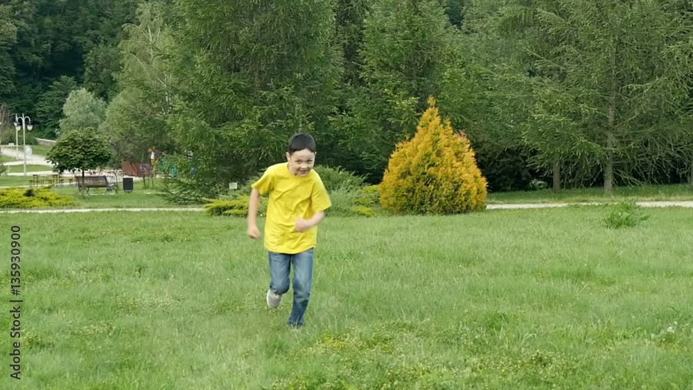 Smiling boy running in a park zone. Slow motion. Smiling boy running in a park zone. Slow motion.
