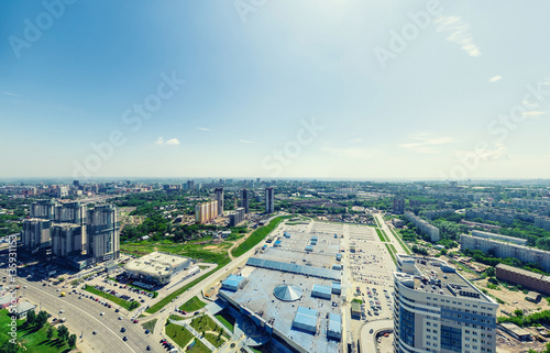 Aerial city view with crossroads and roads, houses, buildings, parks and parking lots, bridges. Urban landscape. Copter shot. Panoramic image.