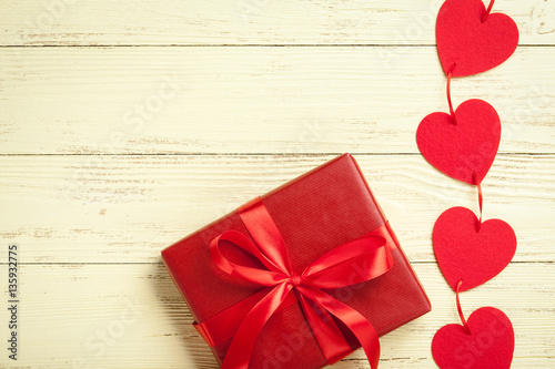 Red hearts and gift box on yellow wooden background