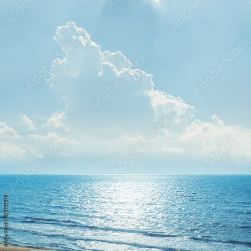 clouds in blue sky over sea and reflections of sun