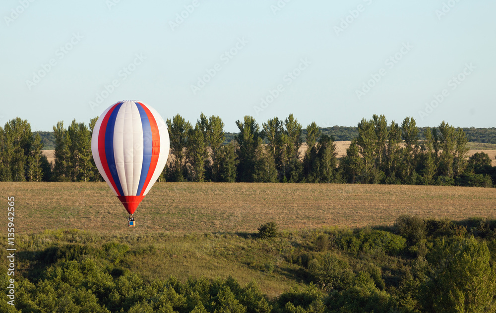 Obraz premium Balloons fly over the green fields, hills in summer