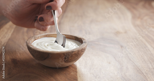 eating organic yogurt with spoon from wood bowl  4k photo