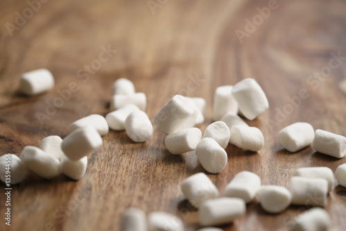 falling white marshmallows on wooden table, slight motion blur