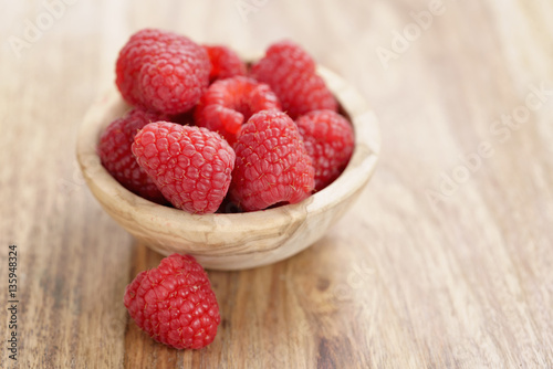 wood bowl full of ripe raspberries on old wooden table, with copy space