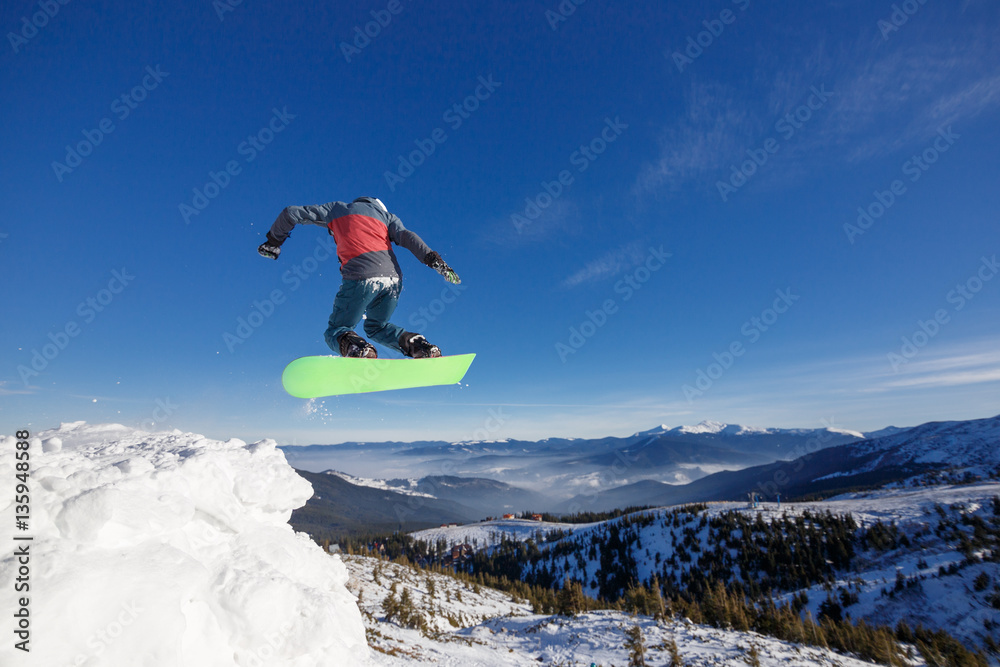 Jumping snowboarder in mountains in ski resort on blue sky background Dragobrat