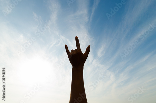 silhouette human hand in shape of love against the sky and sun.