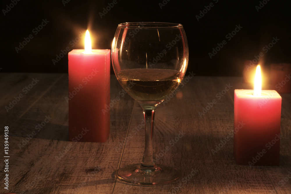 glass of wine or cognac and red candle on a wooden background. glass of wine or cognac and red candle on a wooden background.
