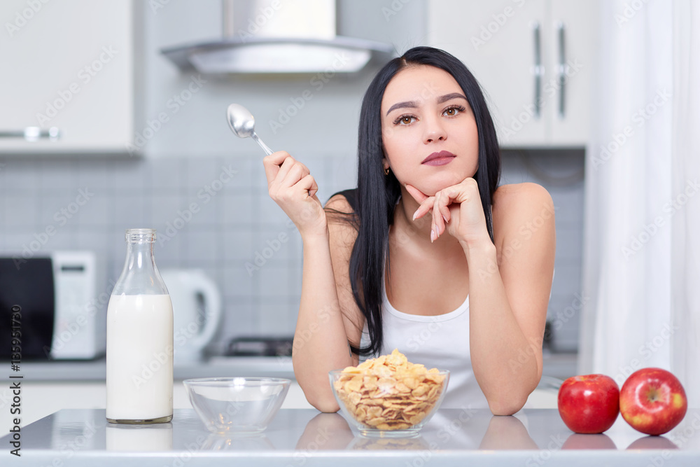Young woman in white clothes sitting in the kitchen Young woman in white clothes sitting in the kitchen