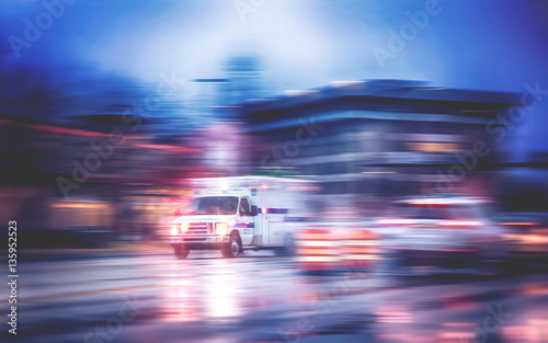 an ambulance racing through the rain on a stormy night with motion blur photo
