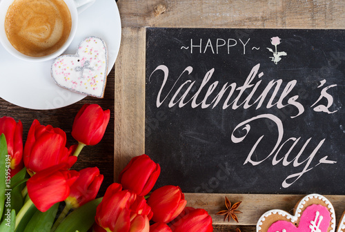 Valentines day coffee with red tulips bouquet, copy space on blackboard with happy valentines day greetings © neirfy