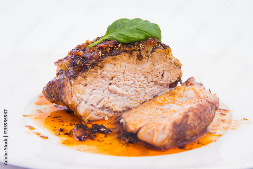 Roast pork decorated with basil on a white plate Roast pork decorated with basil on a white plate