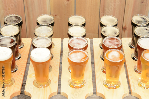 Beer flight sample showing variety of beer with paddle on rustic wooden table