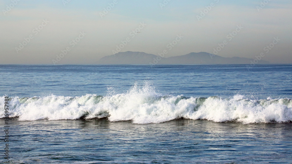 Waves along the beach with islands in the background