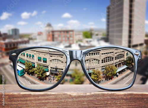  hipster glasses on a park bench or table with a cityscape in the city